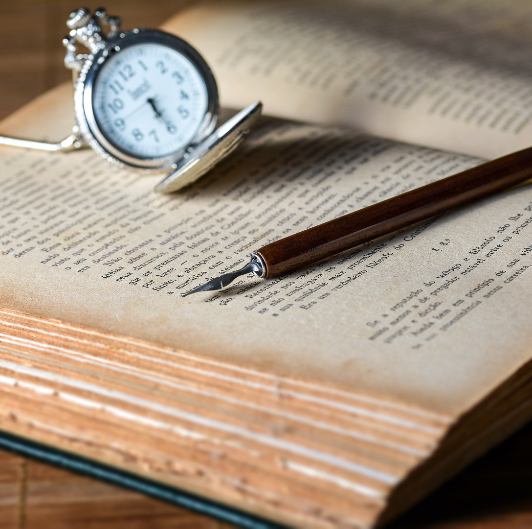 Open book with fountain pen and open pocket watch lying on top